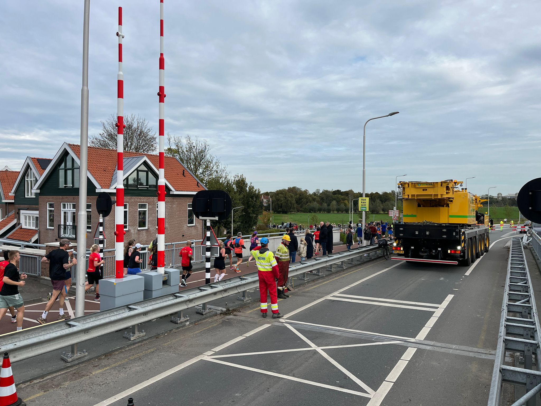 Foto 3: Terwijl de laatste hardlopers van de Amsterdam Marathon langsrennen komt de hijskraan voor het inhijsen van de hulpbrug en oprijplaten.