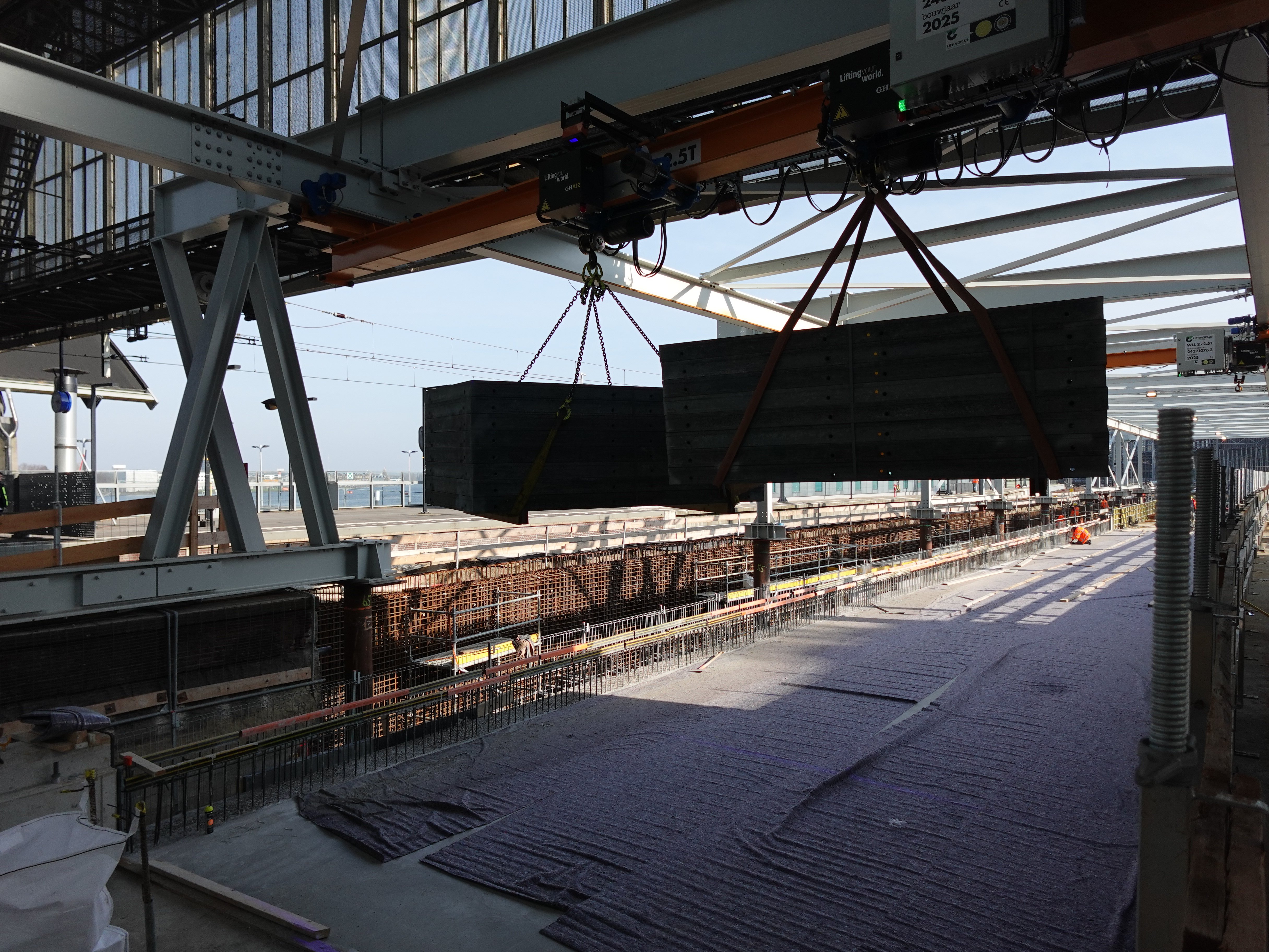 Bovenloopkraan in actie met betondelen.