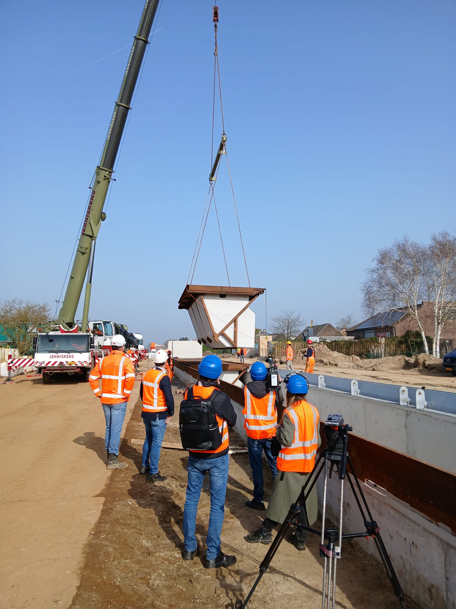Onder het toeziend oog van de cameraploeg wordt een klep van de zelfsluitende waterkering op zijn plek gehesen.