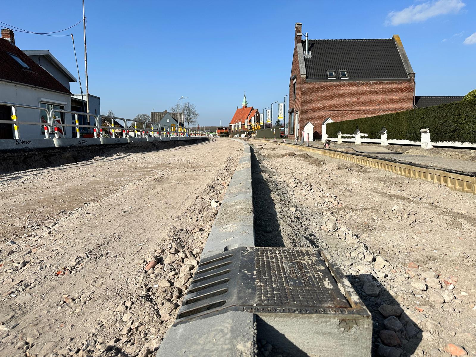 Op de voorgrond zie je een kolk. Rechts in beeld het fiets-voetpad.