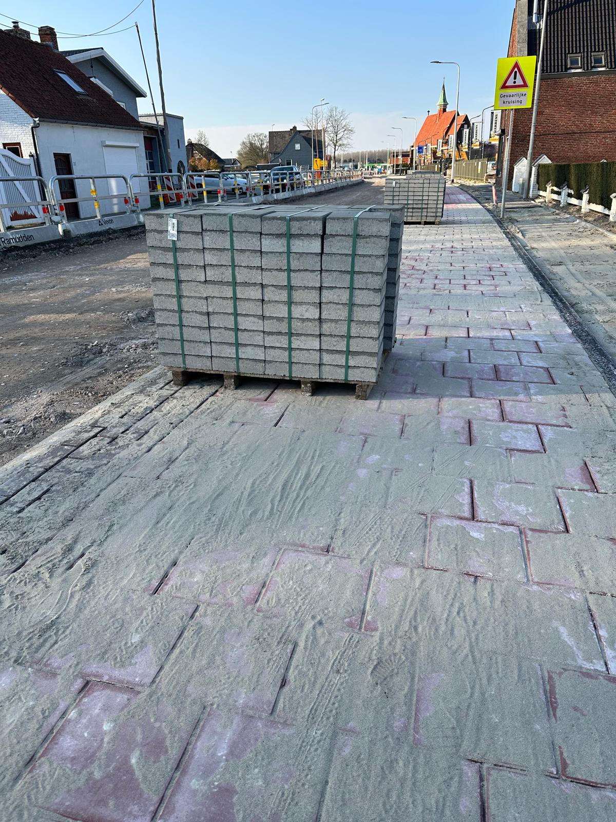 De stenen voor het voetpad stonden vorige week nog te wachten en liggen nu grotendeels al in de stoep!