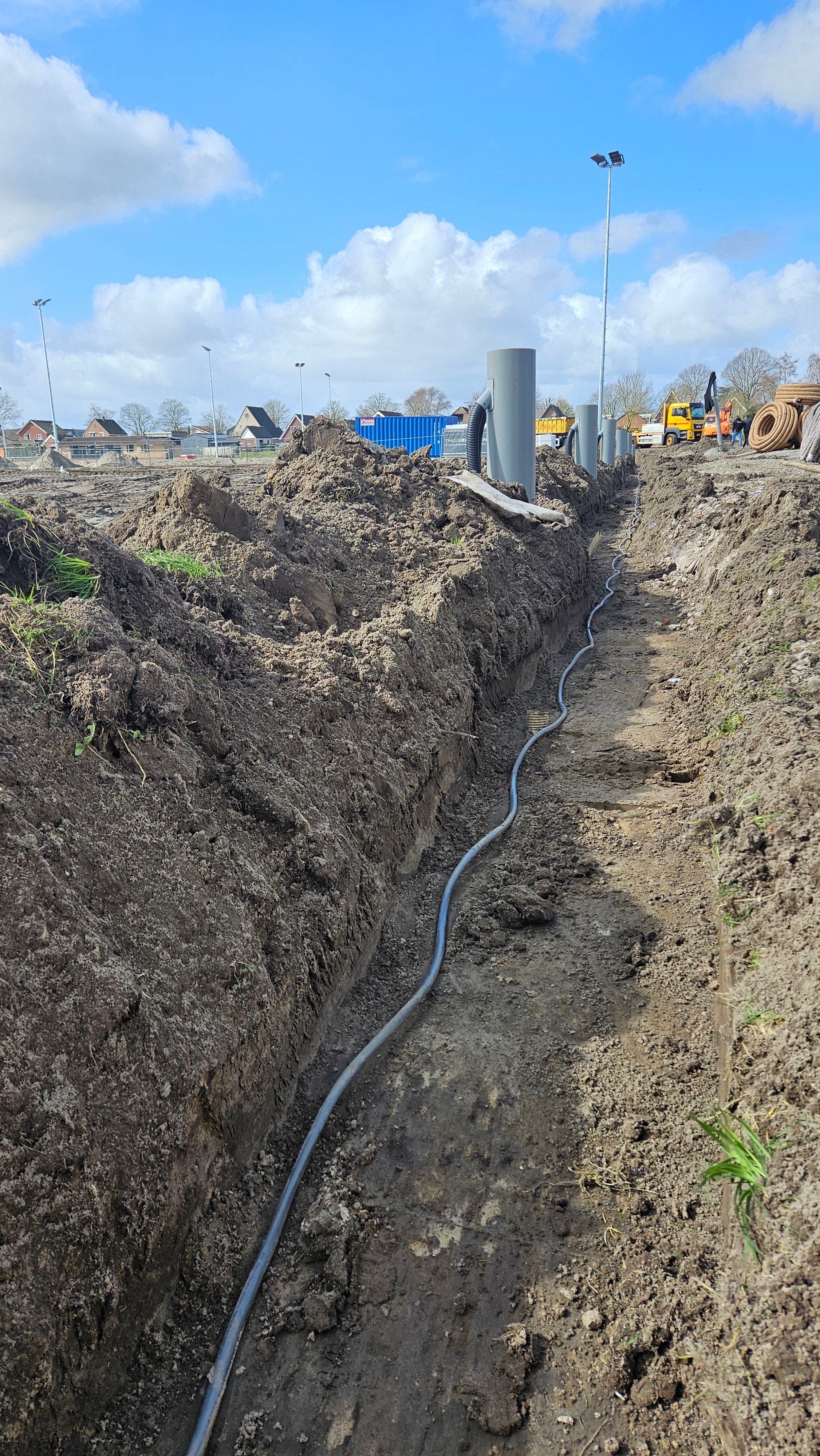Aanleggen van de verlichtingskabel. Ook de drainageputten zijn zichtbaar.
