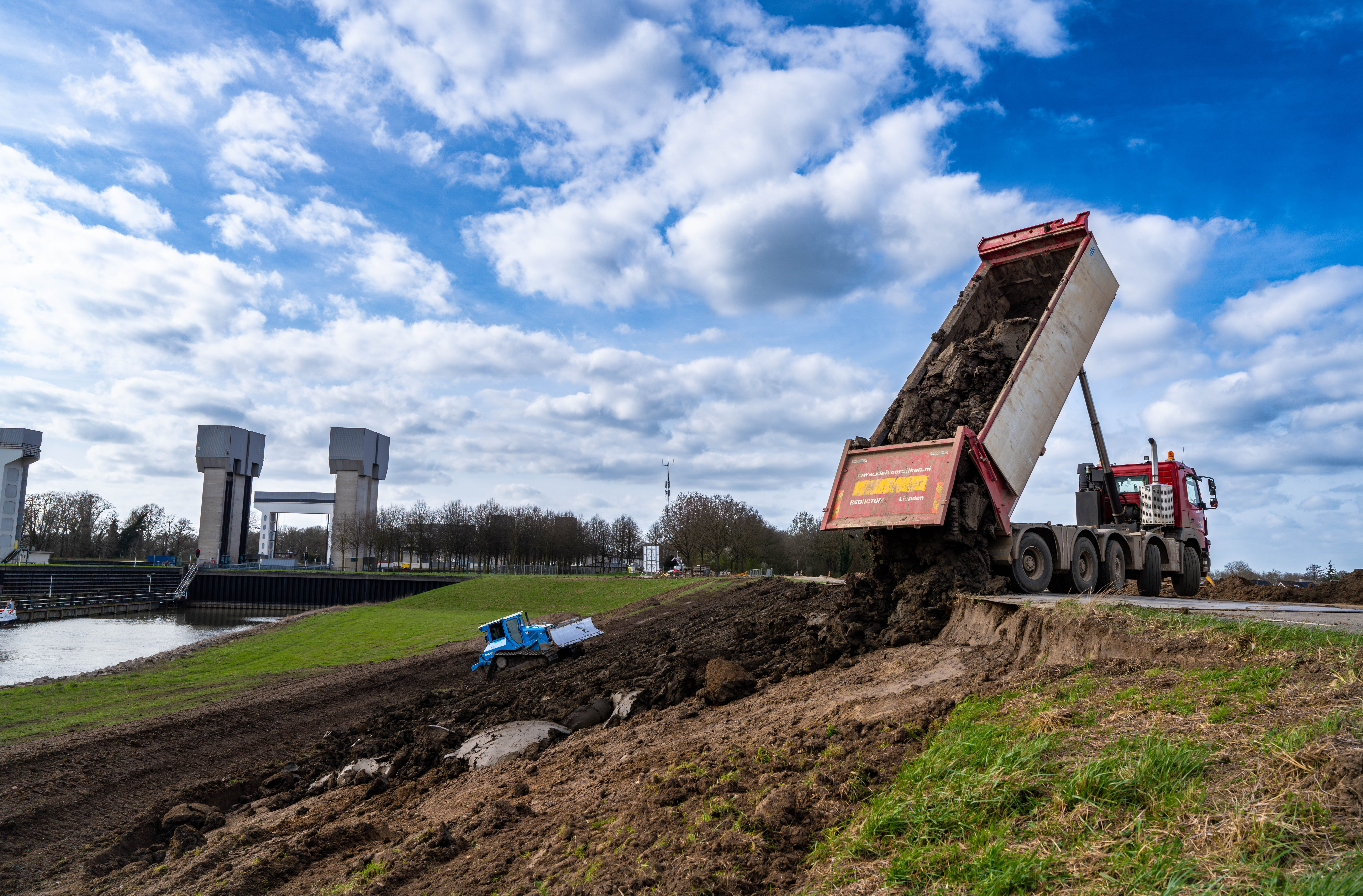 Klei wordt aangebracht om de buitenzijde van de dijk te versterken.