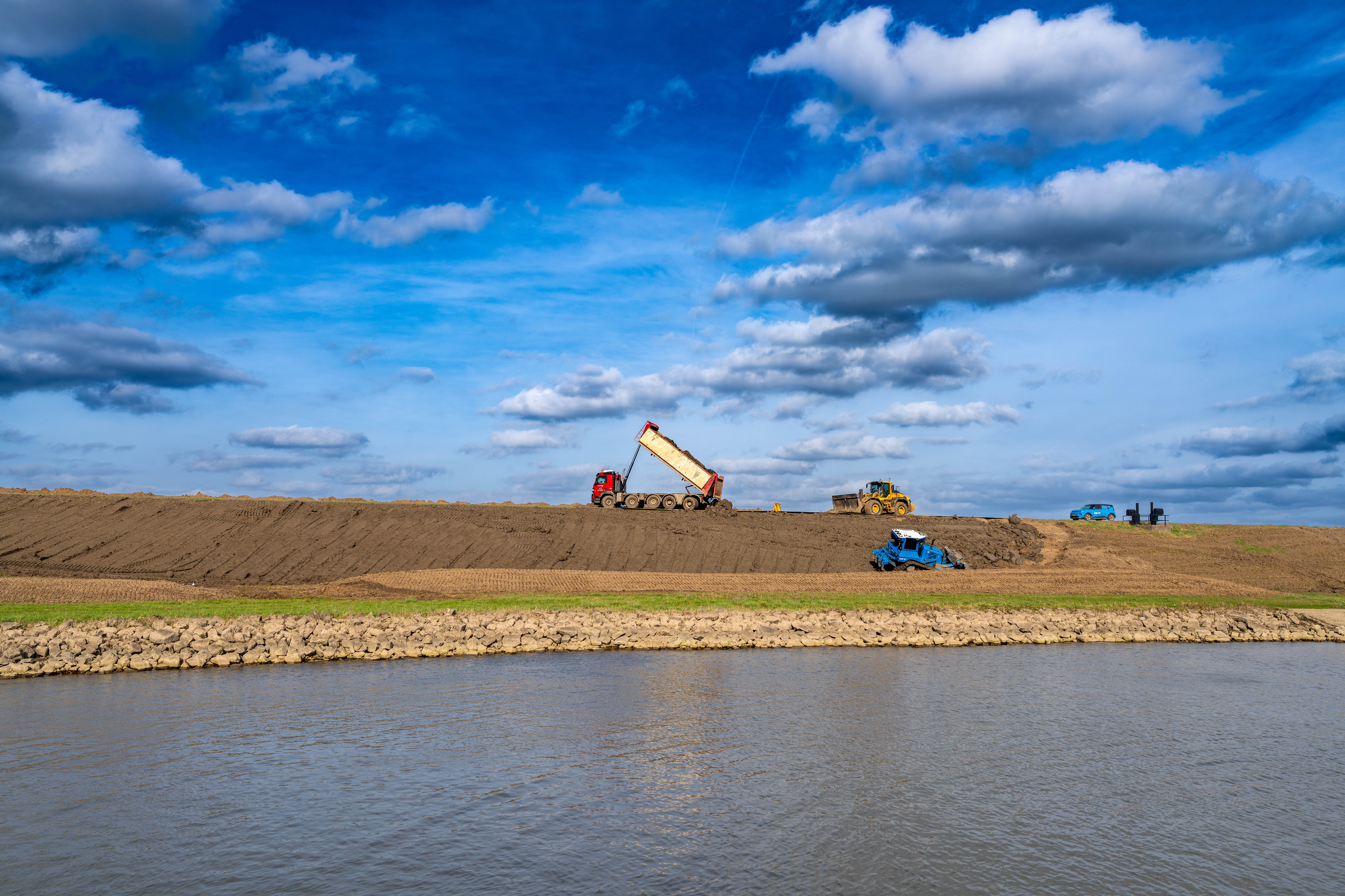 Zicht op de grondwerkzaamheden vanaf de overzijde van het water.