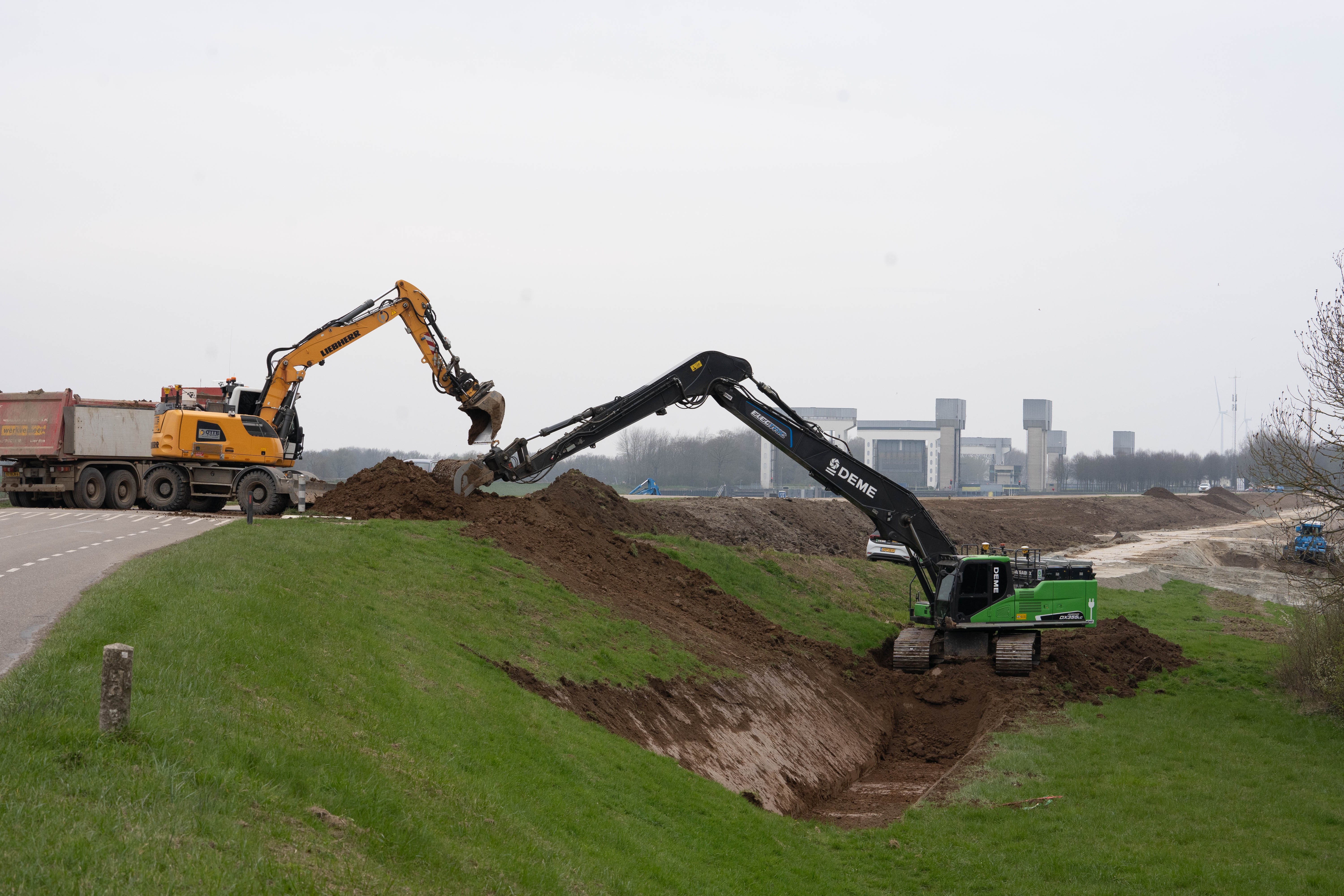 Graafmachines in actie bij het uitgraven van de heisleuf waarin later de damwanden worden geplaatst.