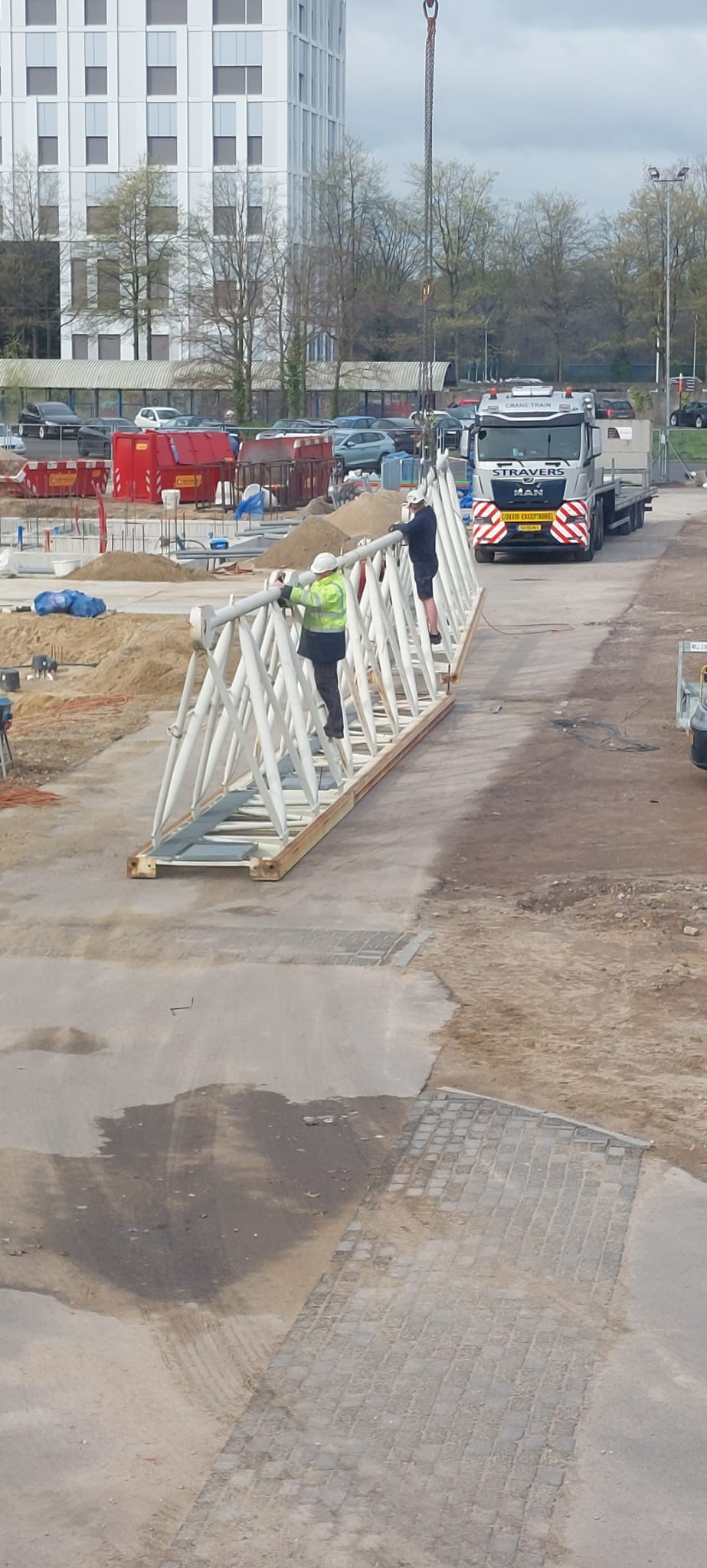 Sommige delen van de giek worden op de grond gemonteerd en daarna in de lucht bevestigd aan de torenkraan.
