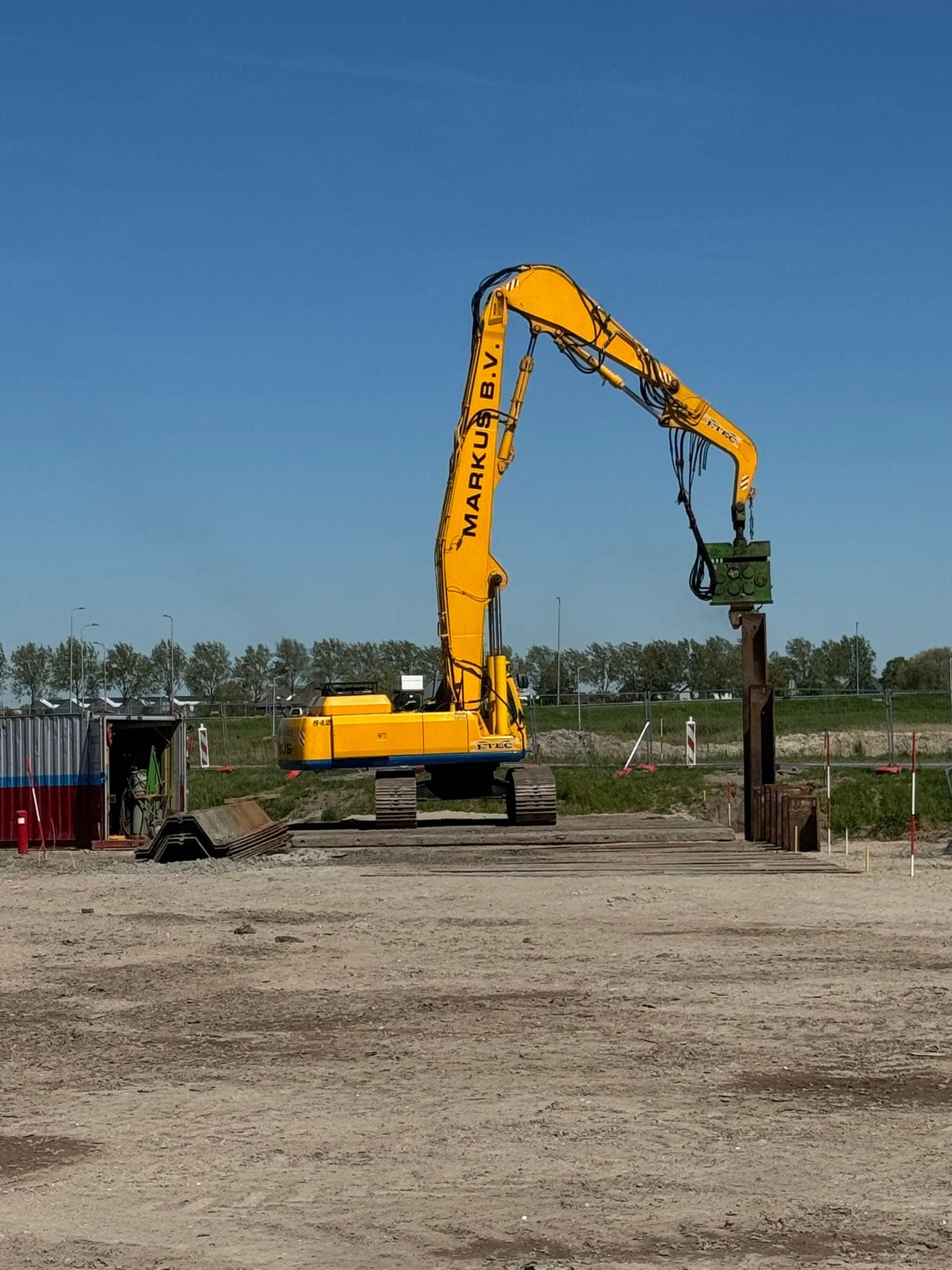 Hier slaat een kraan een damwand in de grond.