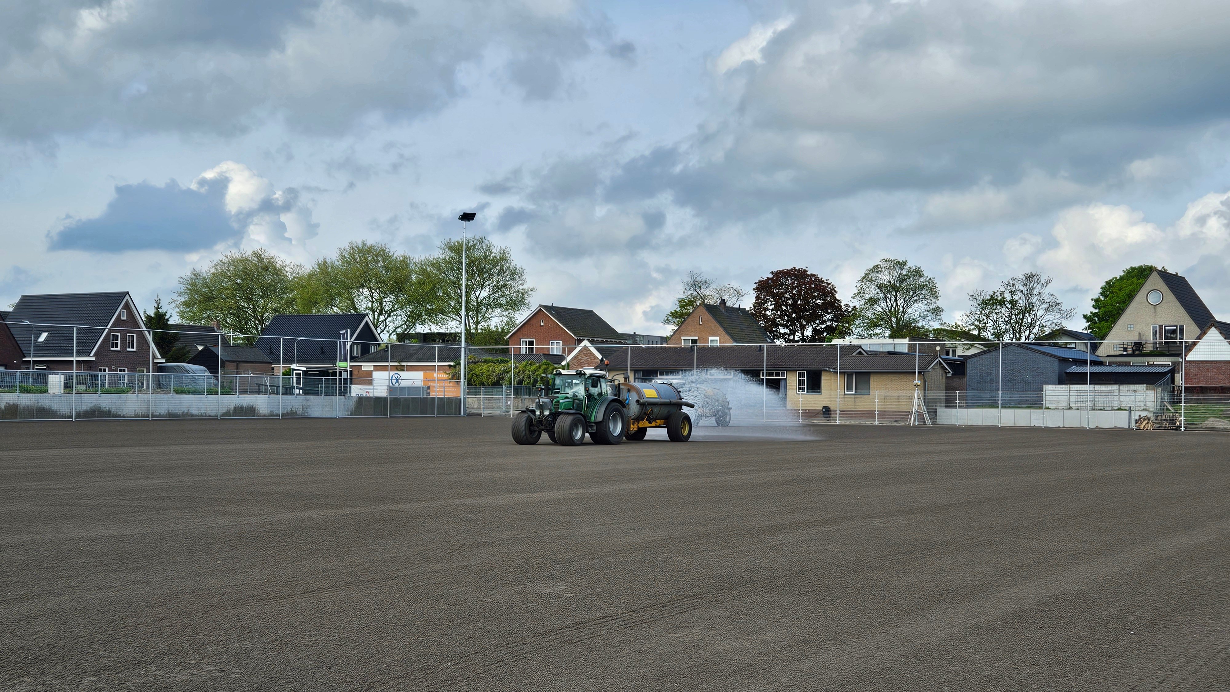 Bewateren van het kunstgrasveld om te voorkomen dat de grond wegwaait.