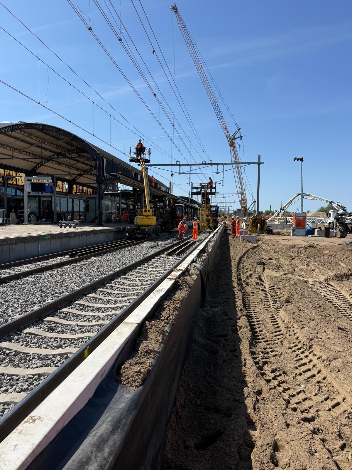 Laatste werkzaamheden aan de bovenleiding. Ook zie je aan de rechterkant van het spoor de rand van het nieuwe perron 5-6.