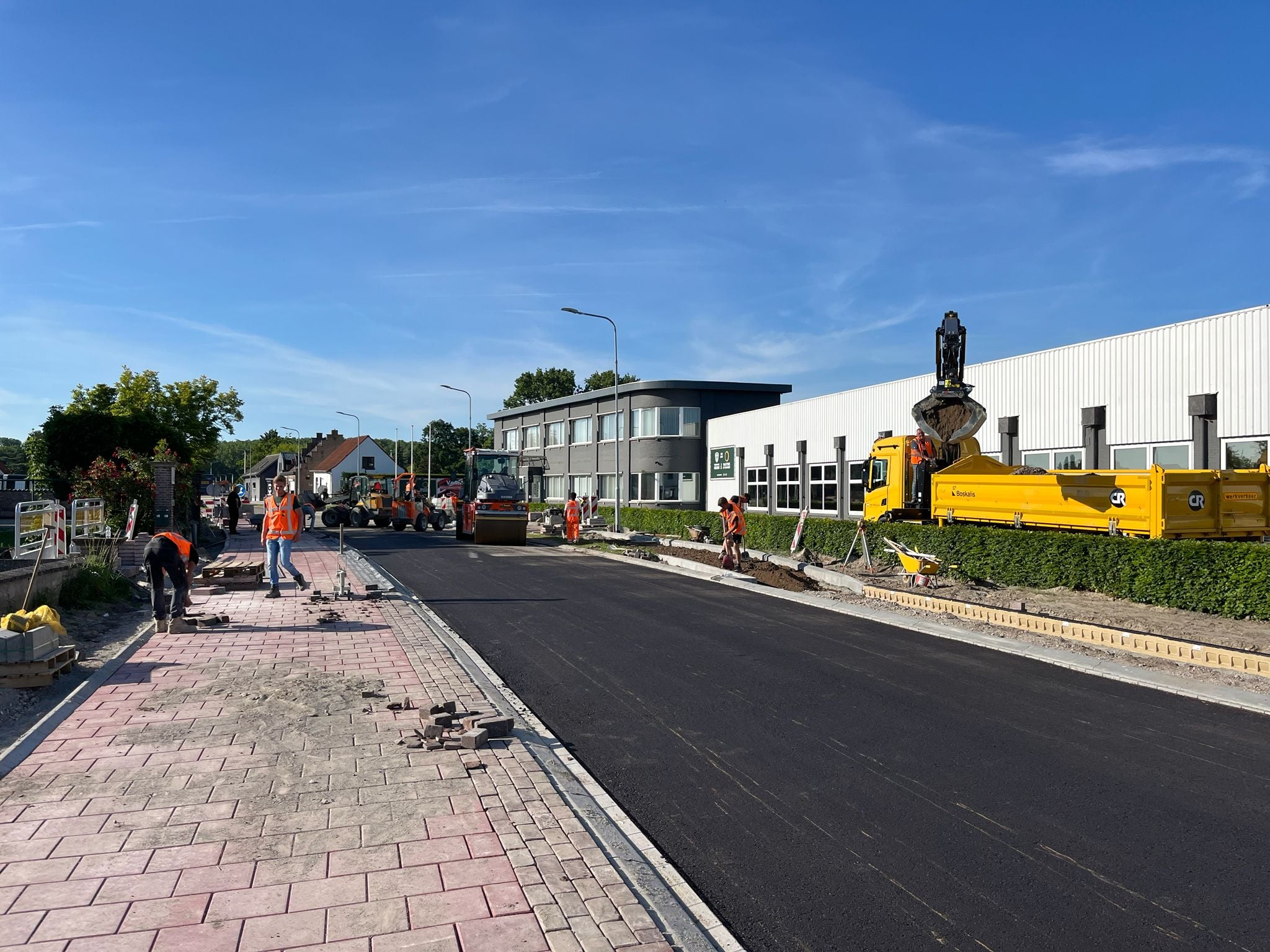 De nieuwe asfaltbaan. het voet-fietspad wordt aangelegd (links). Rechts de aanleg van het voetpad.