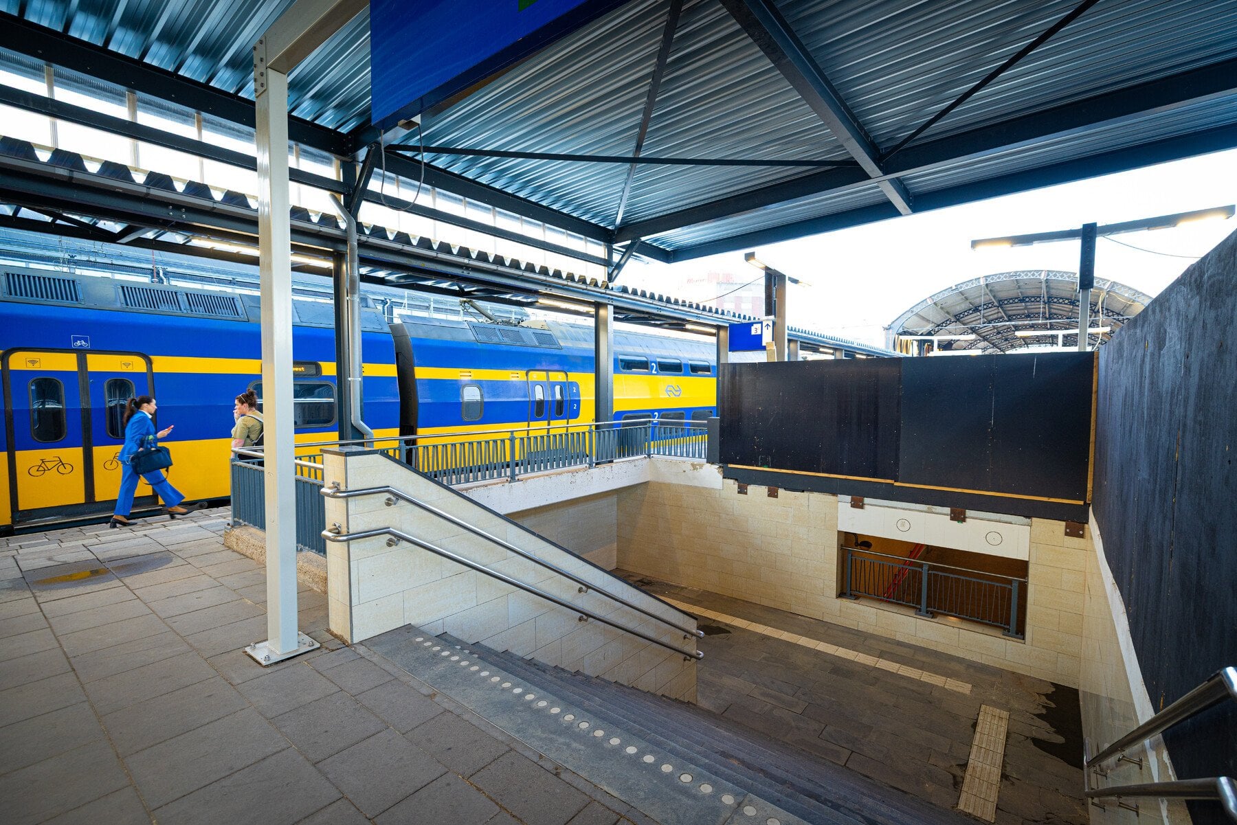 Beeld als je als reiziger de trap neemt op perron 3-4. Je ziet de tijdelijke kap en een bouwschutting.