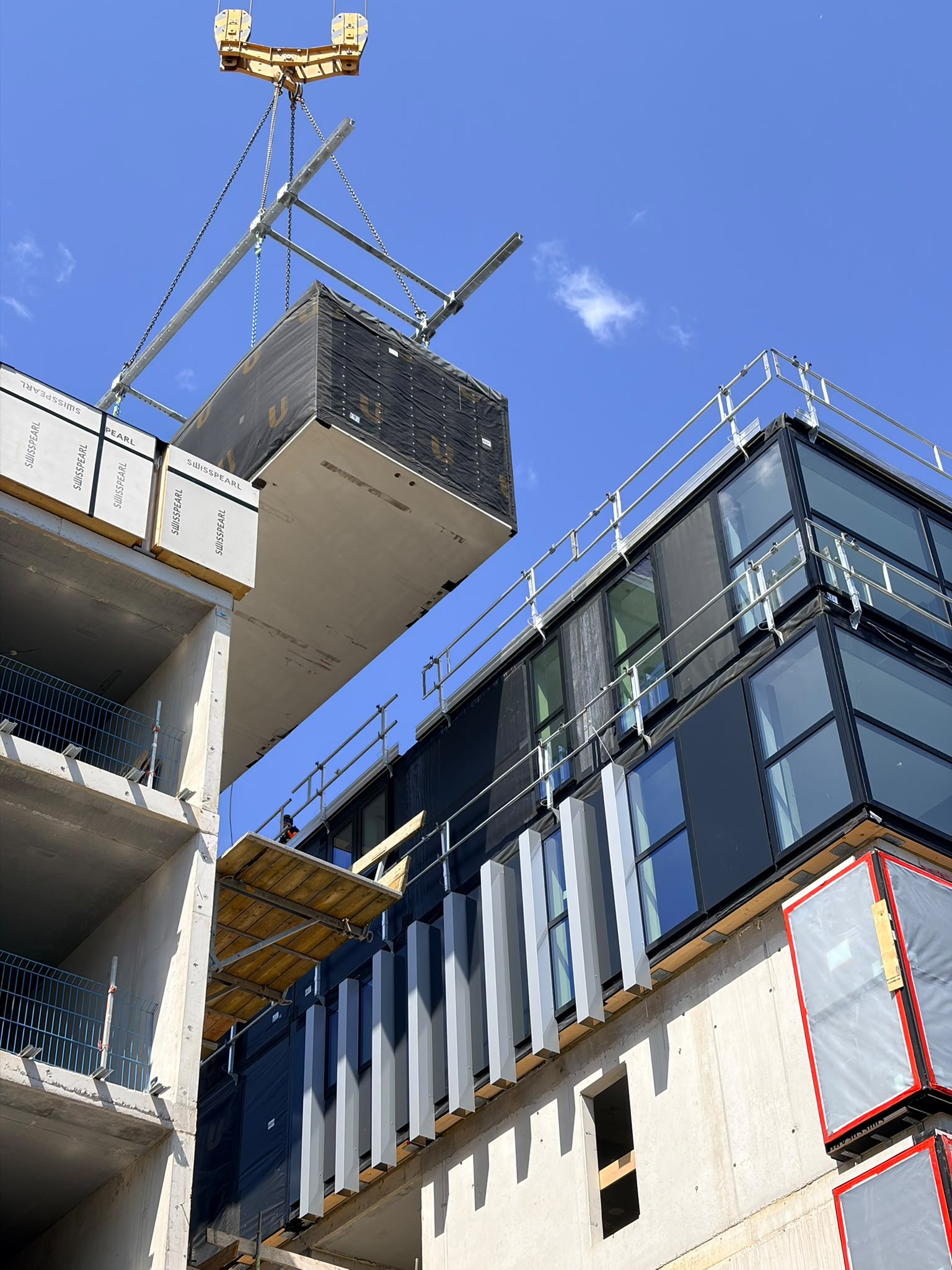 Toren 1: Hijsen van een module, de eerste gevelafwerking is zichtbaar