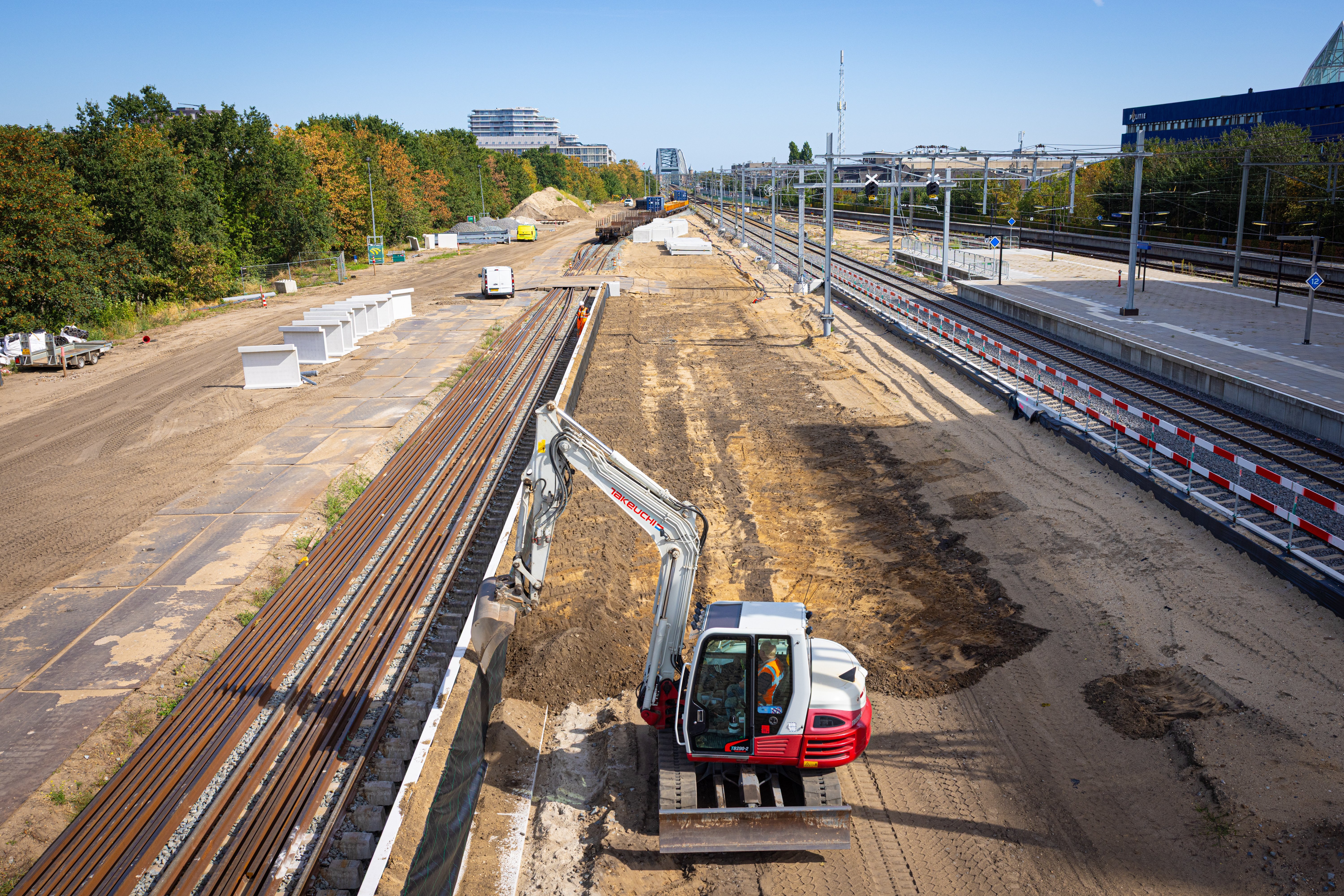 Het eerste deel van de keerwanden staat langs het spoor. De kraan vult alvast een deel aan met grond.
