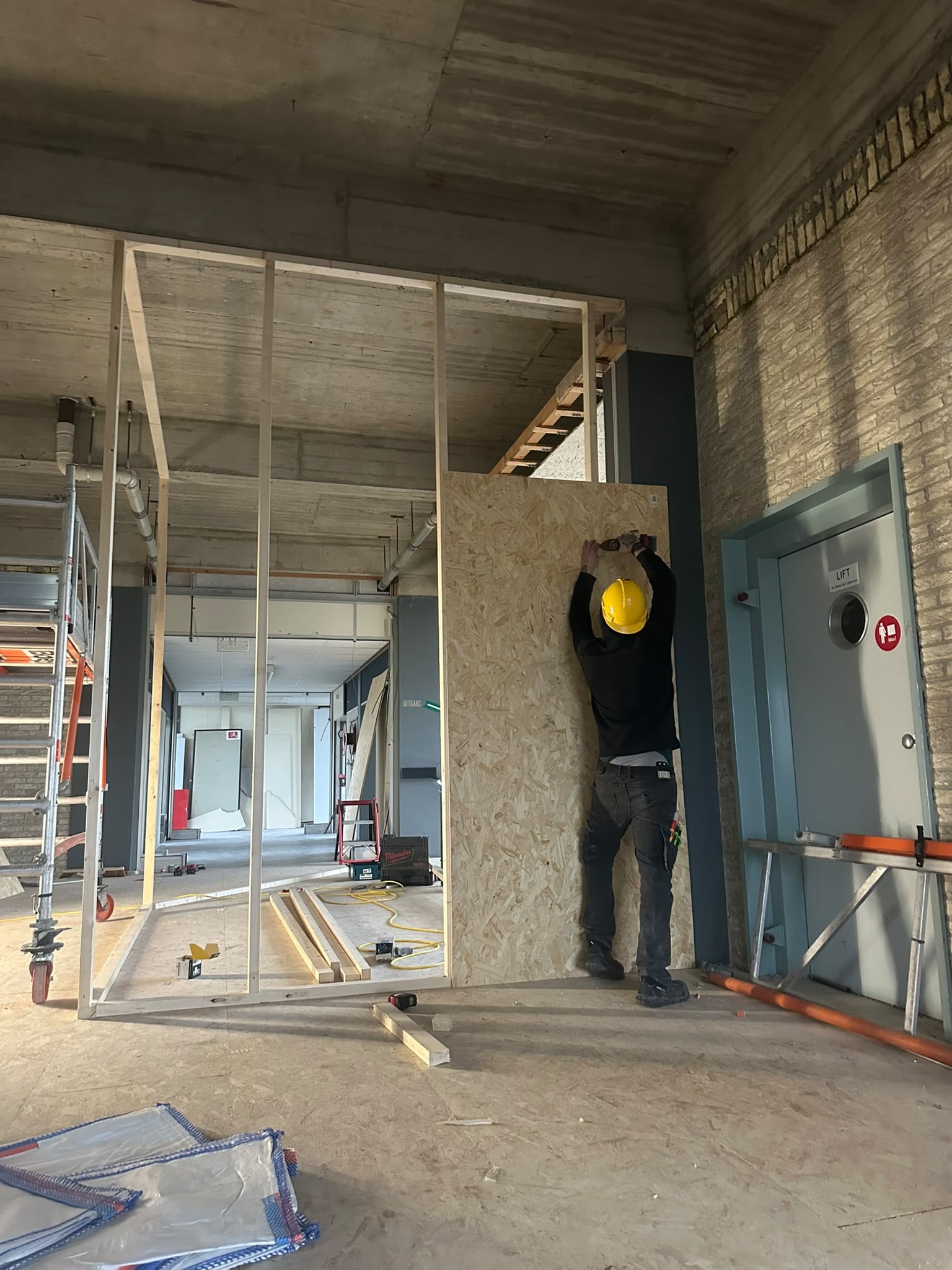 Tijdelijke vaste wanden worden geplaatst om verschillende werkgebieden te compartimenteren.